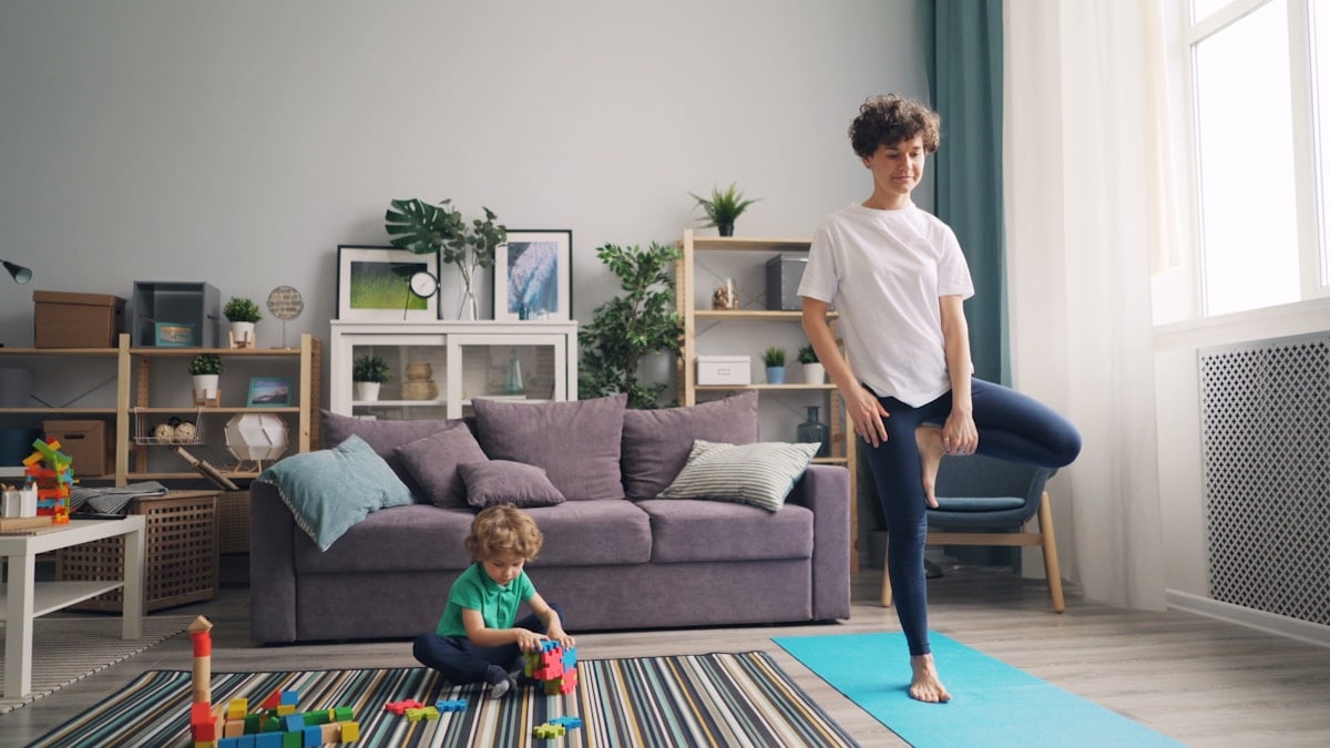 a woman standing in a living room next to a child